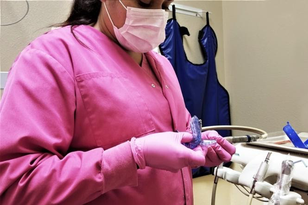 A dental assistant works in the exam room to prepare for the next dental appointment.
