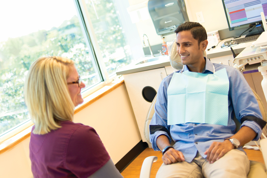 Patient sitting in the dental chair talking to a dentist.