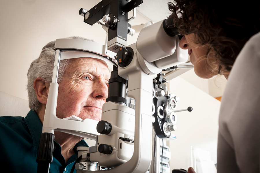 Older adult getting an eye exam from an eye doctor.