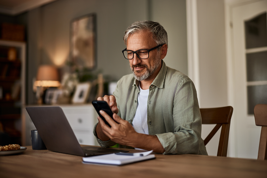 Person on their computer and phone, checking benefits online.