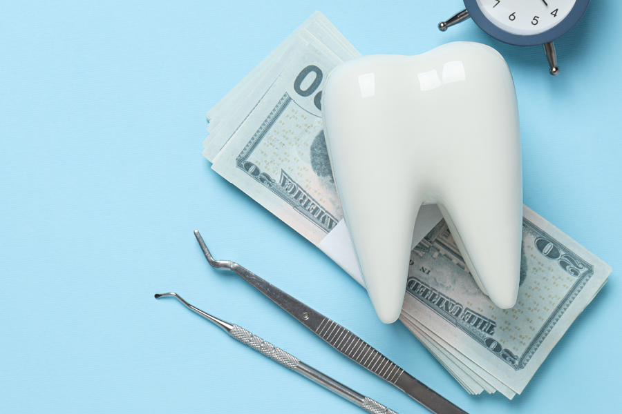Fake tooth, money and dental tools on a table.