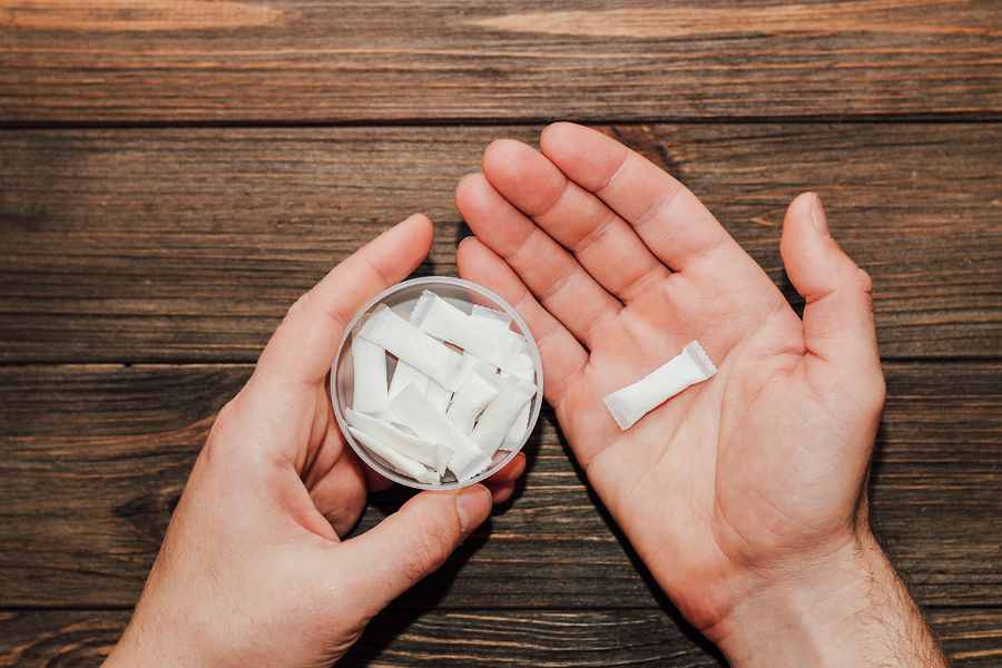 Person holding a can of oral nicotine pouches.