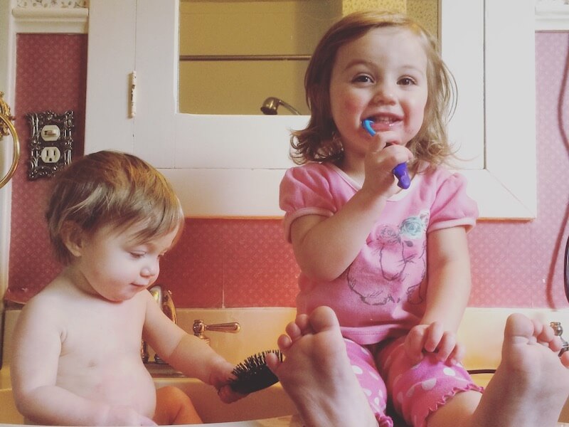 young girls brushing teeth on counter