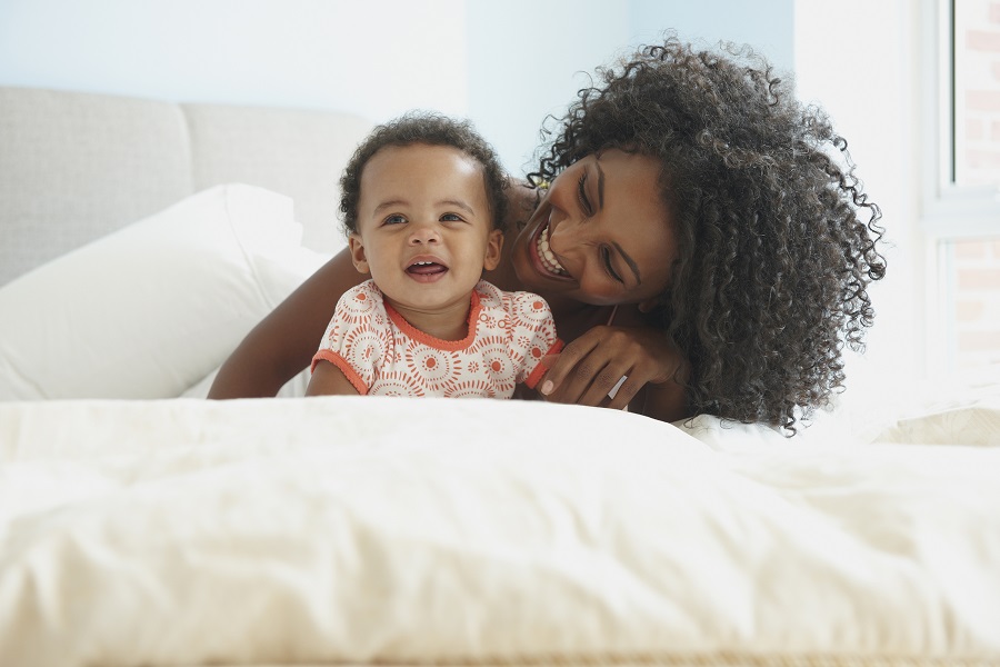 Mother laying on bed with her little baby in her arms