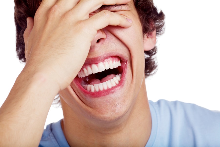 man holding his face while he laughs