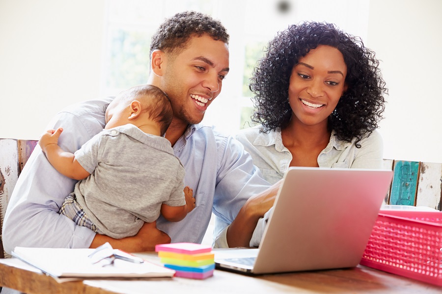 Parents with a baby smiling at computer