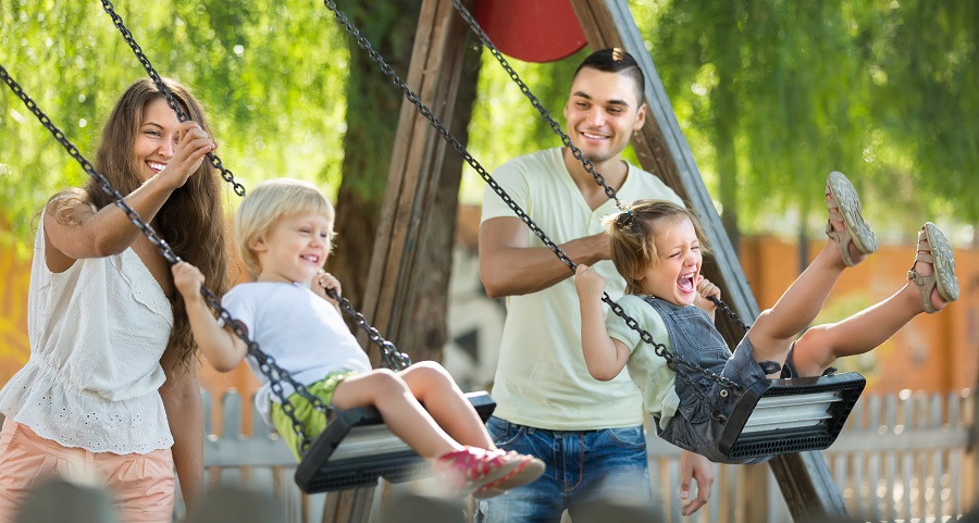 Parents pushing kids on swings