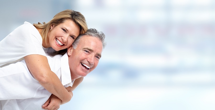 Older man holding his wife on his back while they smile