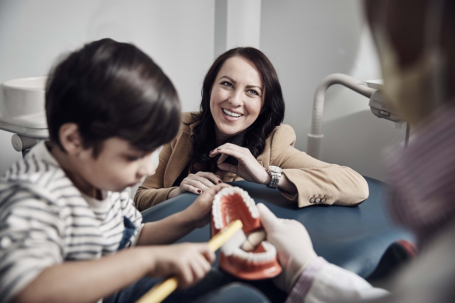 Little boy at dentist playing with dentures