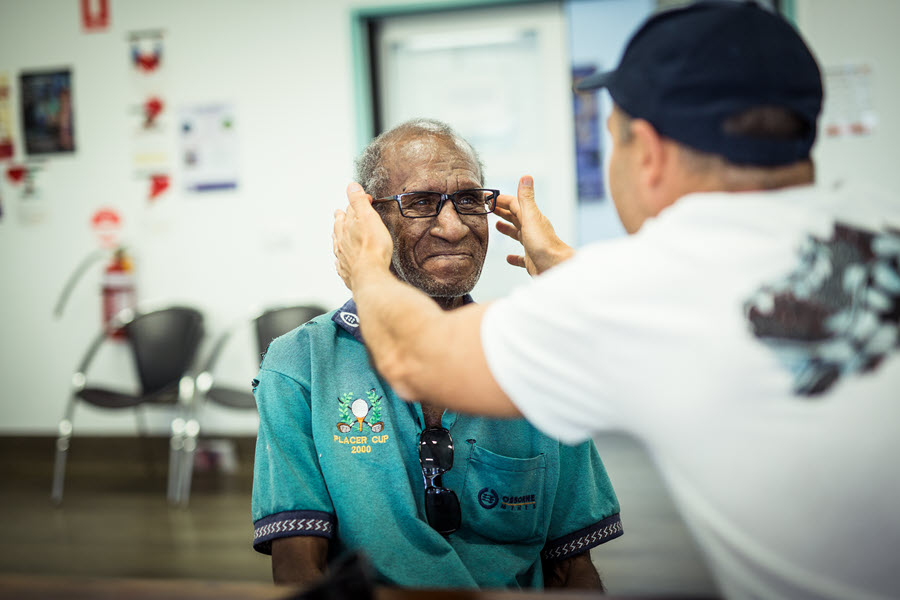 Man fitting glasses on another man