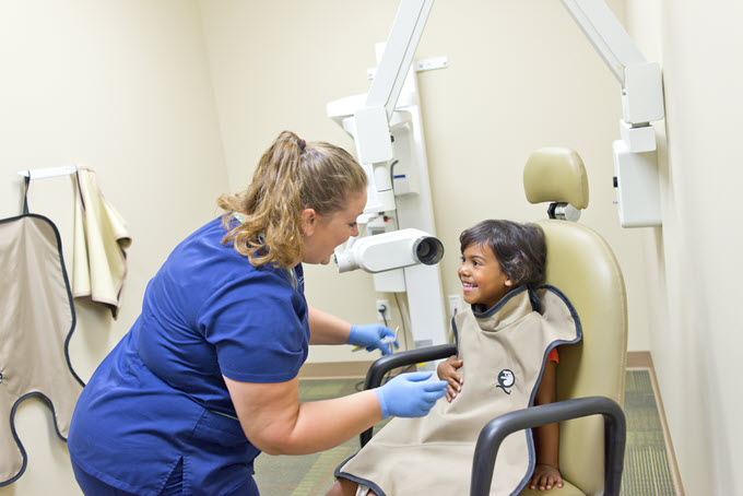Dental assistant with girl in chair getting an x-ray