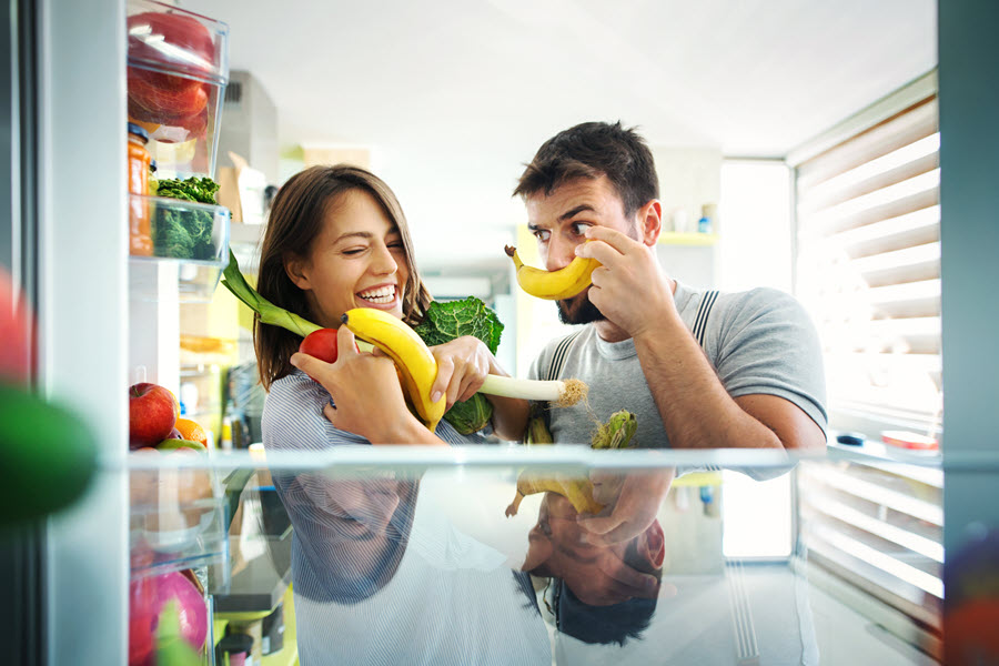 Man and woman getting healthy food out of fridge