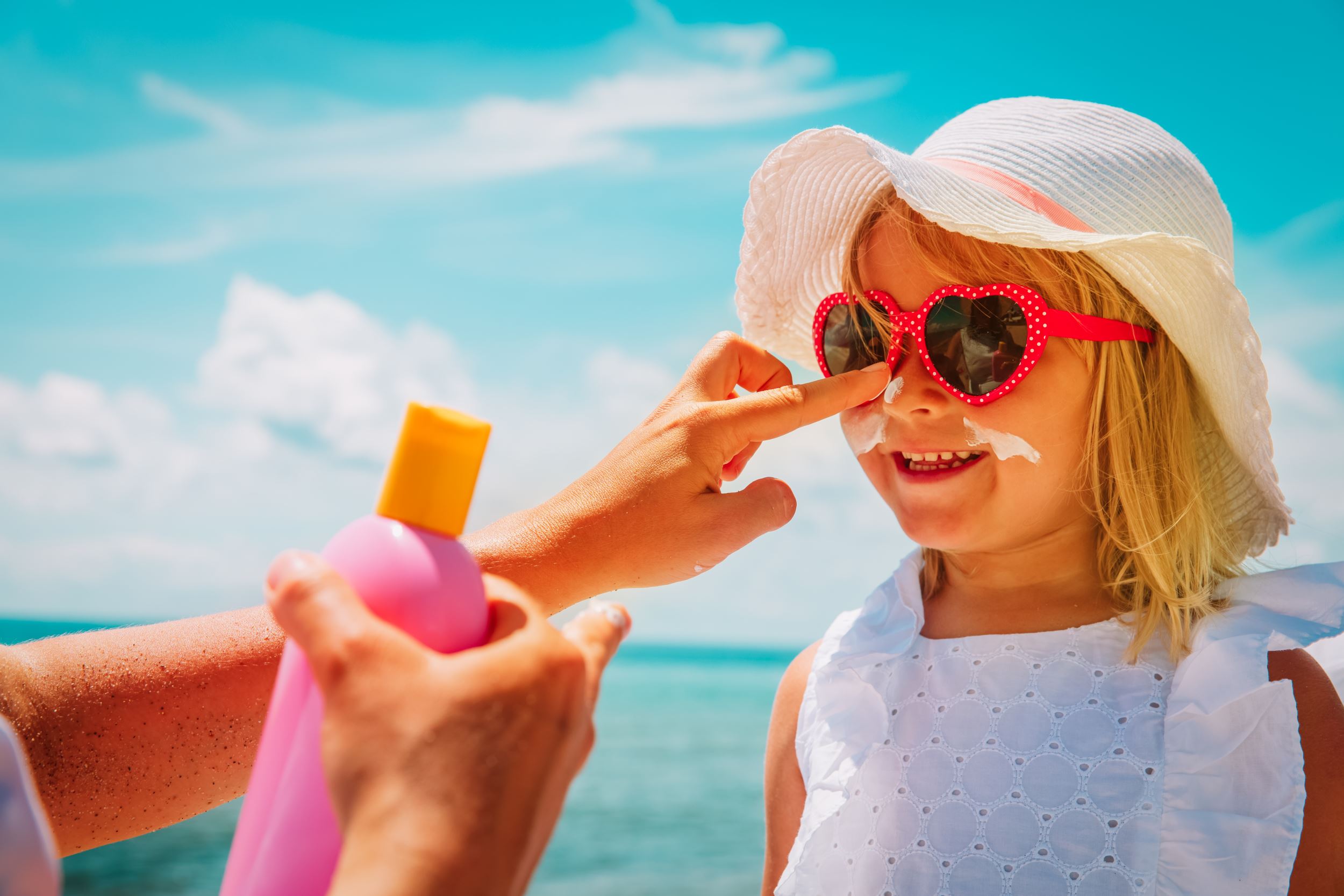 Mother putting sunscreen on girl