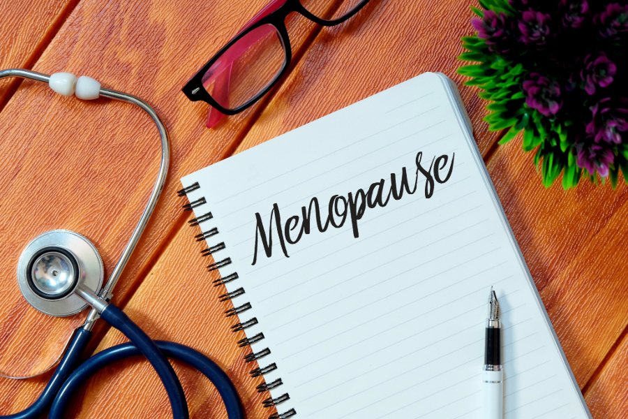 pen, notebook and stethoscope on a table. menopause written on the notebook.
