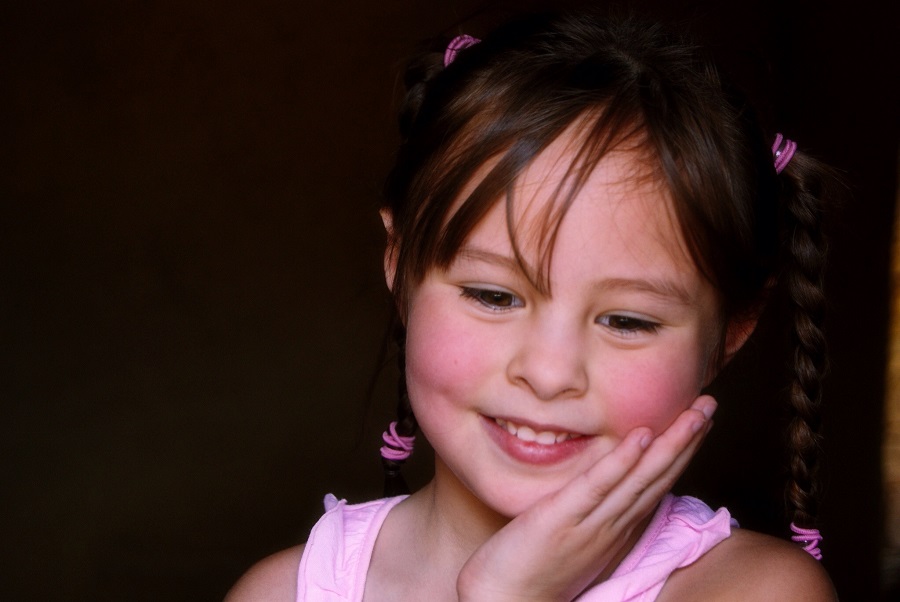 Little girl smiling and holding her cheek