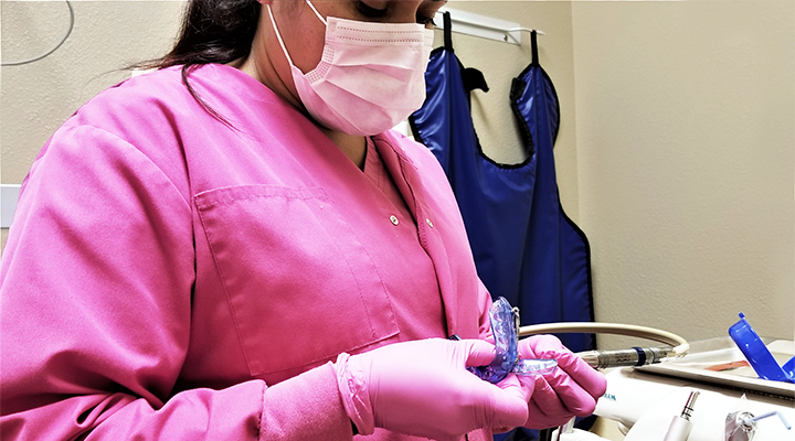 A dental assistant works in the exam room to prepare for the next dental appointment.