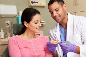 Dentist Demonstrating How To Brush Teeth To Female Patient